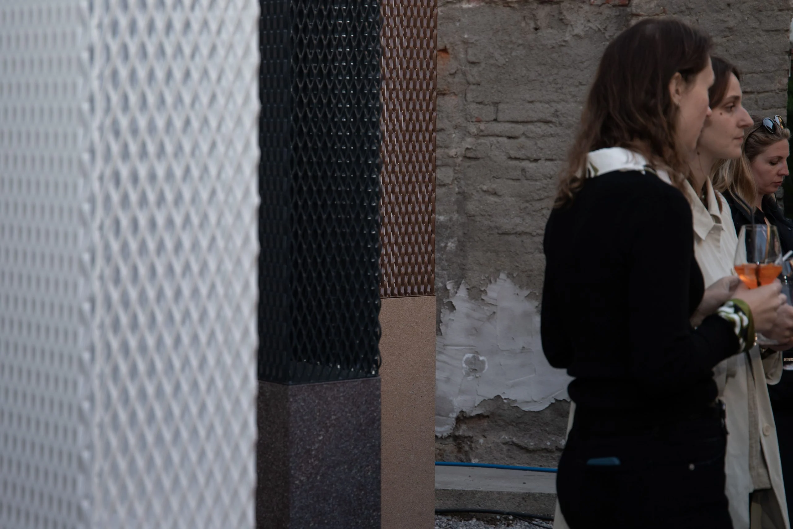 Guests with drinks beside white and black metal mesh columns on stone bases – Everything Is a Party at Fuorisalone, Milan, Italy, 2025 – event design