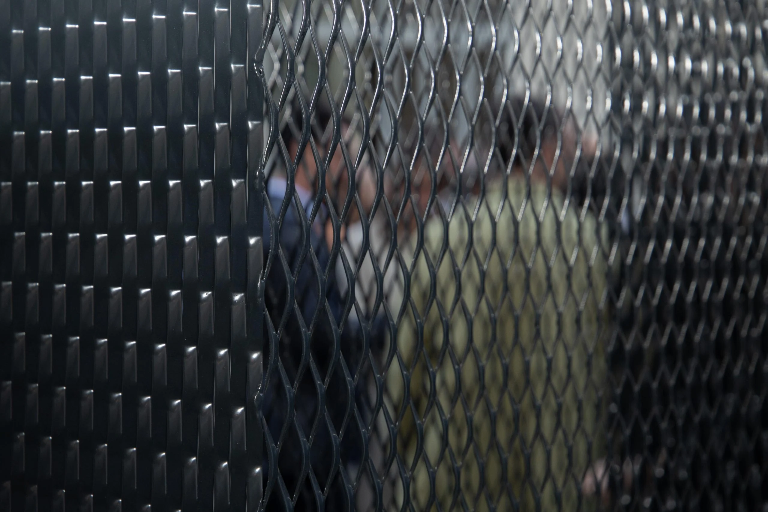 Close-up of black expanded metal mesh panels, a guest blurred behind the mesh – Everything Is a Party at Fuorisalone, Milan, Italy, 2025 – event design