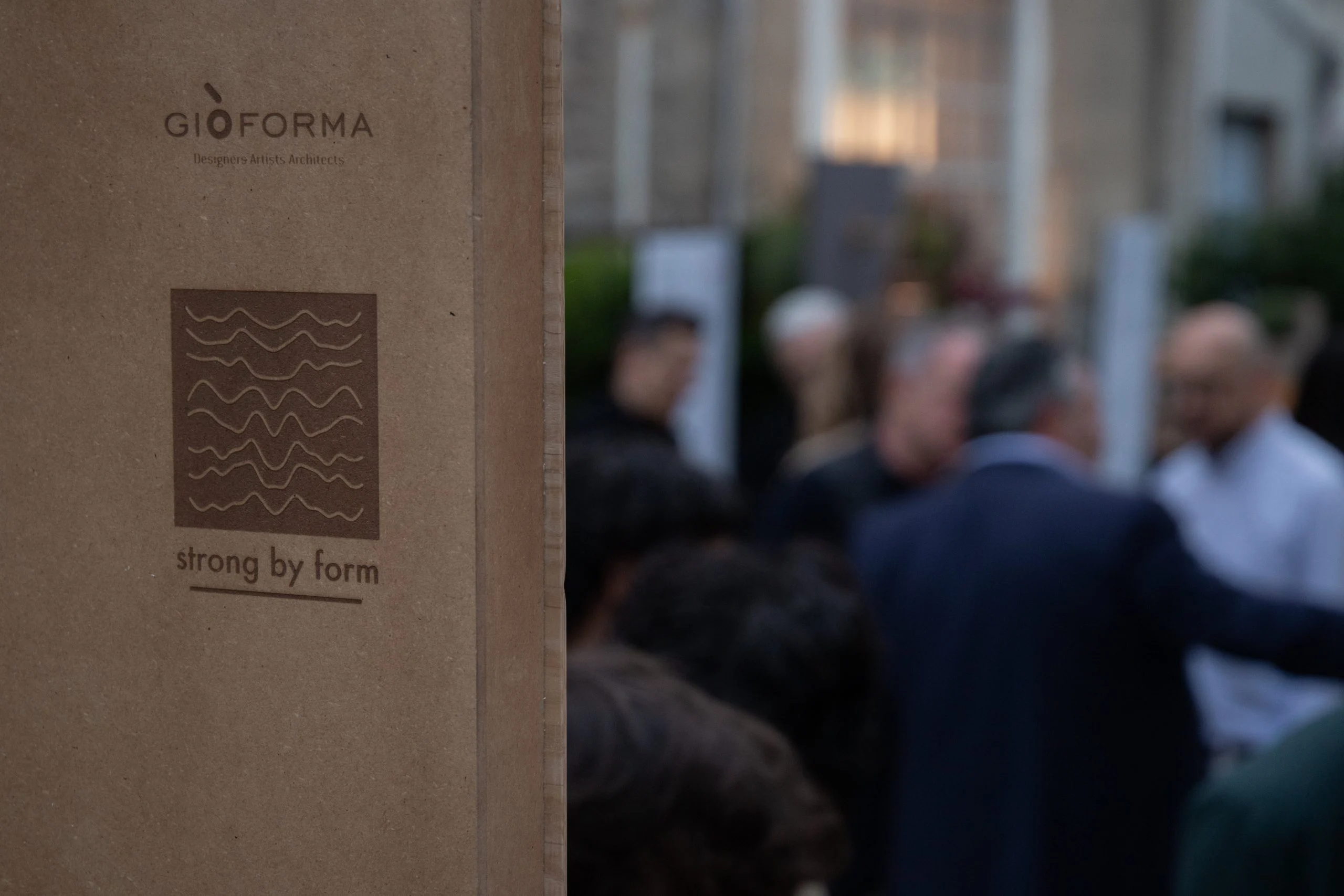 Cardboard box with the Strong by Form logo in the foreground, guests chatting out of focus behind – Everything Is a Party at Fuorisalone, Milan, Italy, 2025 – event design