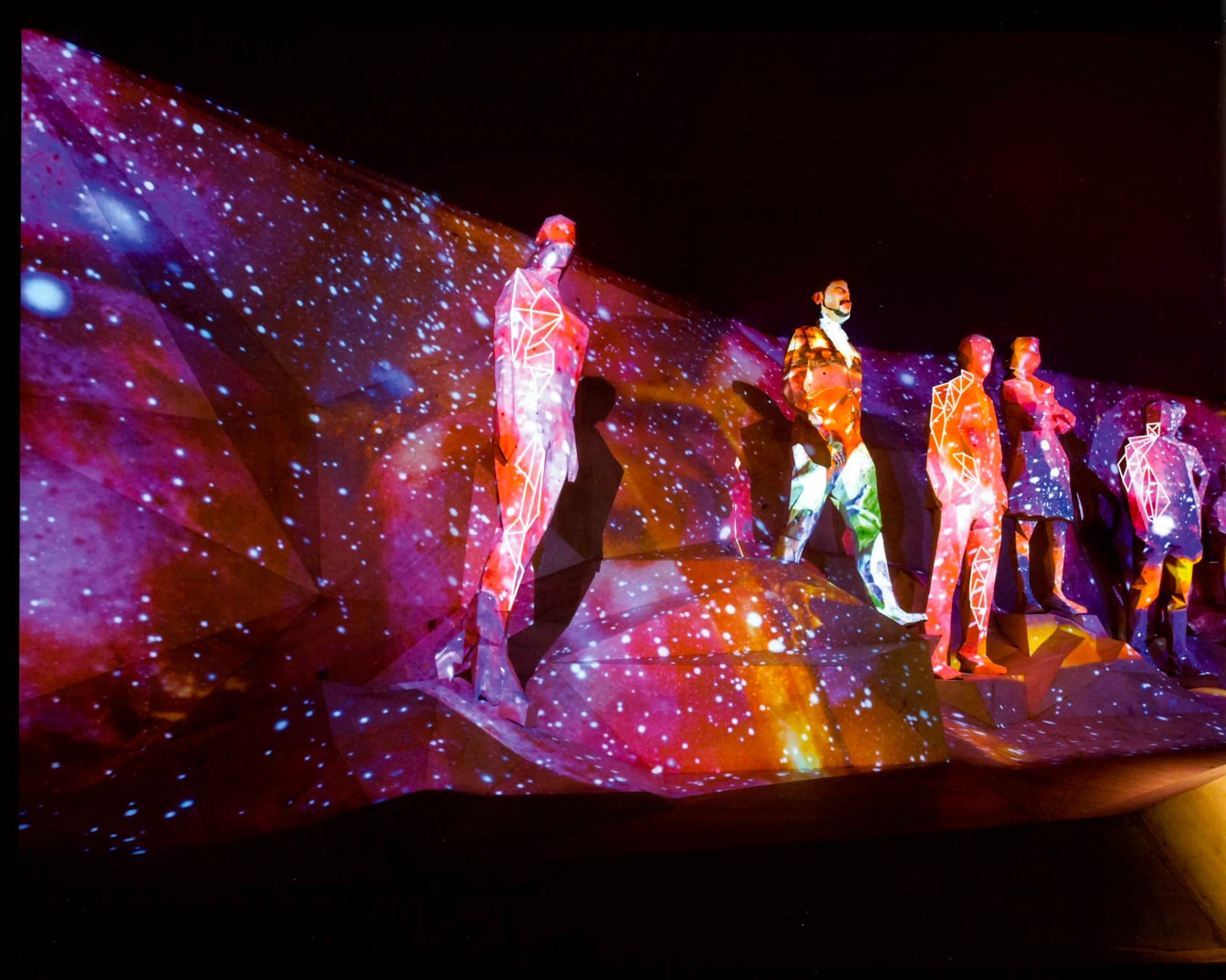 Faceted human figures on a rocky wall covered in a colourful starry projection – Italian Pavilion at Expo 2015, Milan, Italy – exhibition design