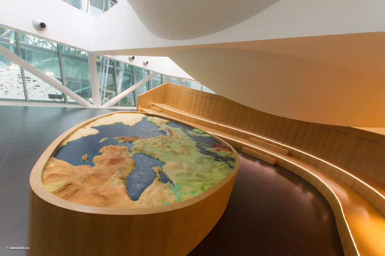 Raised relief map of Italy and the Mediterranean on an oval wooden base, with a curved timber bench – Italian Pavilion at Expo 2015, Milan, Italy – exhibition design