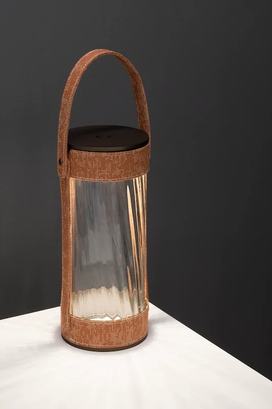 Lantern with terracotta woven strap and ribbed glass on a white table, dark background – AlUla Lantern for Artemide, Milan, Italy, 2025 – lighting design