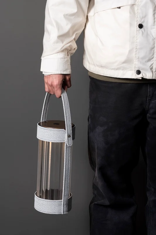 Person carrying a lantern with a grey strap by its handle – AlUla Lantern for Artemide, Milan, Italy, 2025 – lighting design