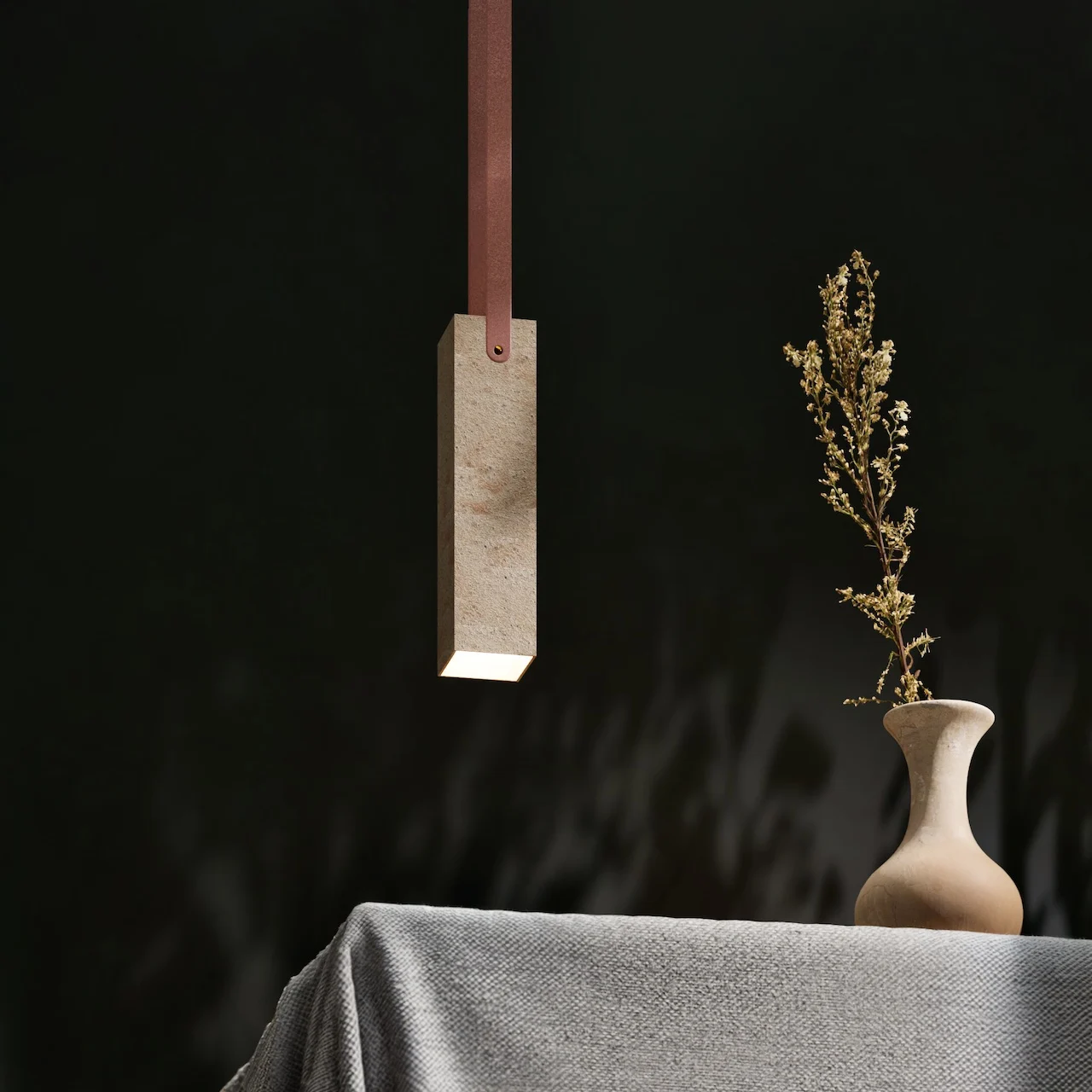 Rectangular stone pendant lamp on a leather strap above a table with a vase of dried flowers – Porfido Pedretti Porphyry Furniture, Milan, Italy, 2025 – product design