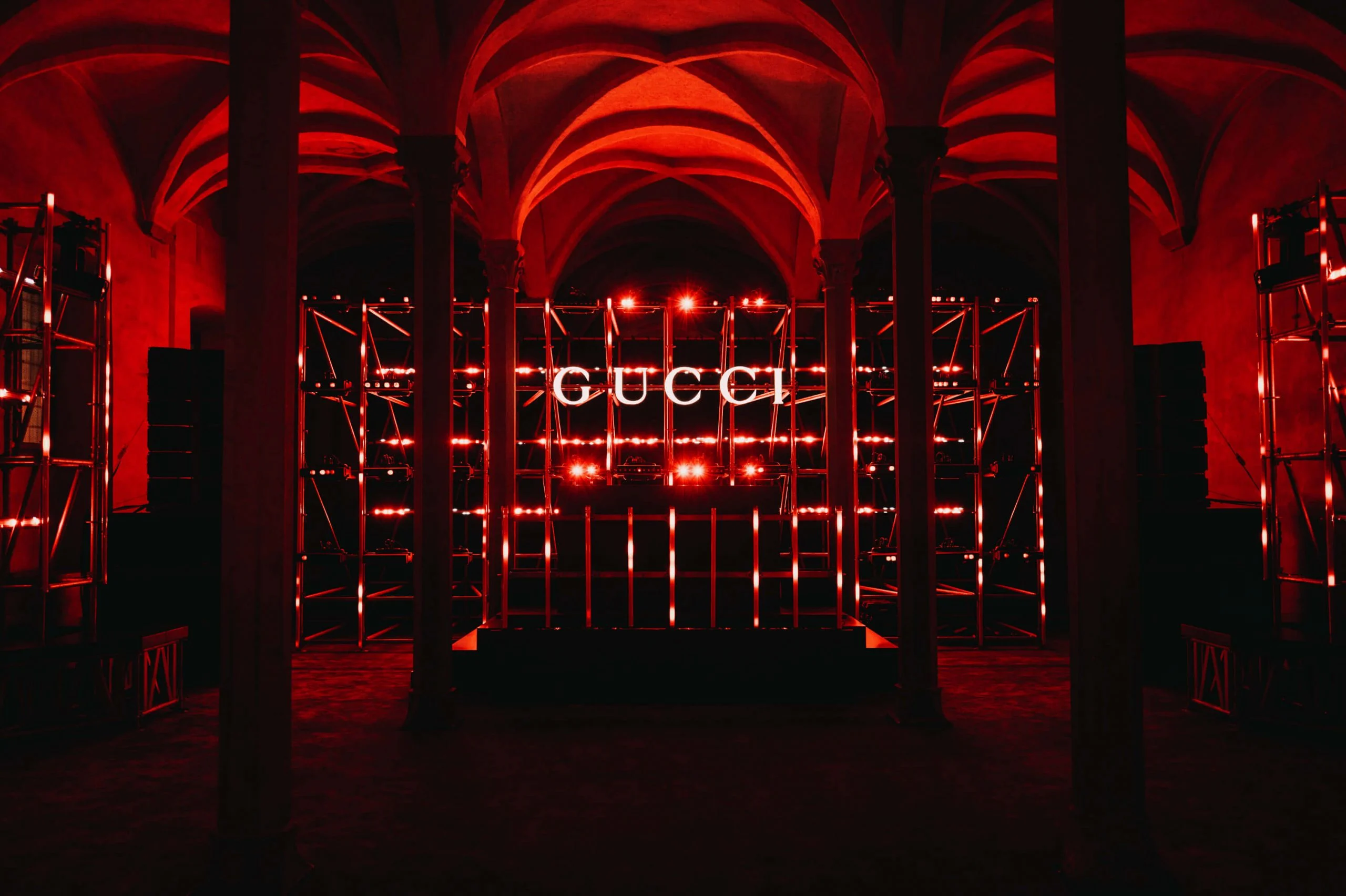Vaulted hall washed in red with scaffolding towers and a GUCCI sign at the centre – Gucci Cruise 2026 Afterparty, Florence, Italy, 2025 – event design