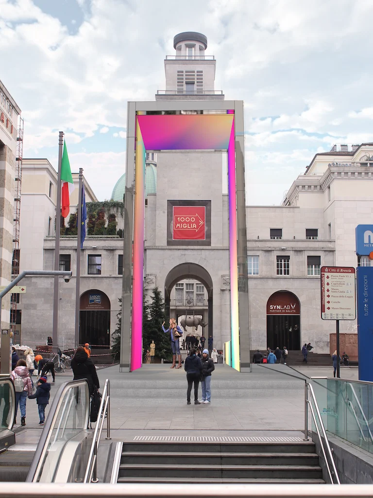 THE GATE portal glowing with iridescent LED screens in a historic square, a clock tower framed behind it – THE GATE 2023, Bergamo and Brescia, Italy – installation design