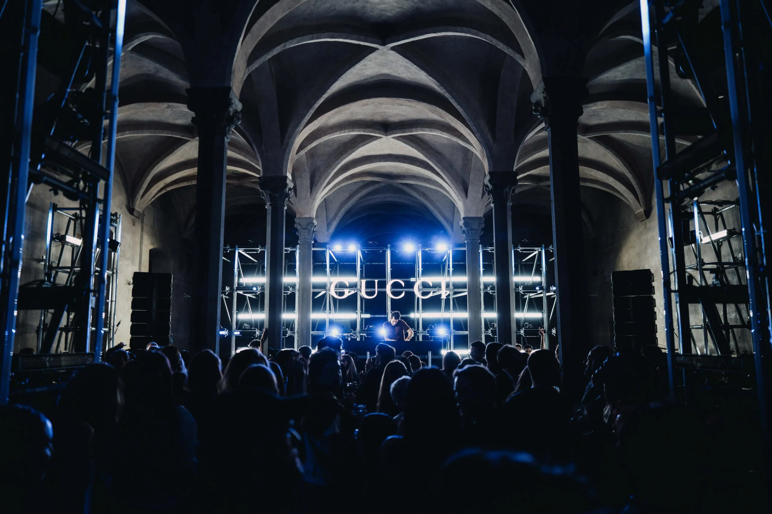 Crowd under the vaulted ceiling facing a DJ booth with a GUCCI sign and white lights – Gucci Cruise 2026 Afterparty, Florence, Italy, 2025 – event design