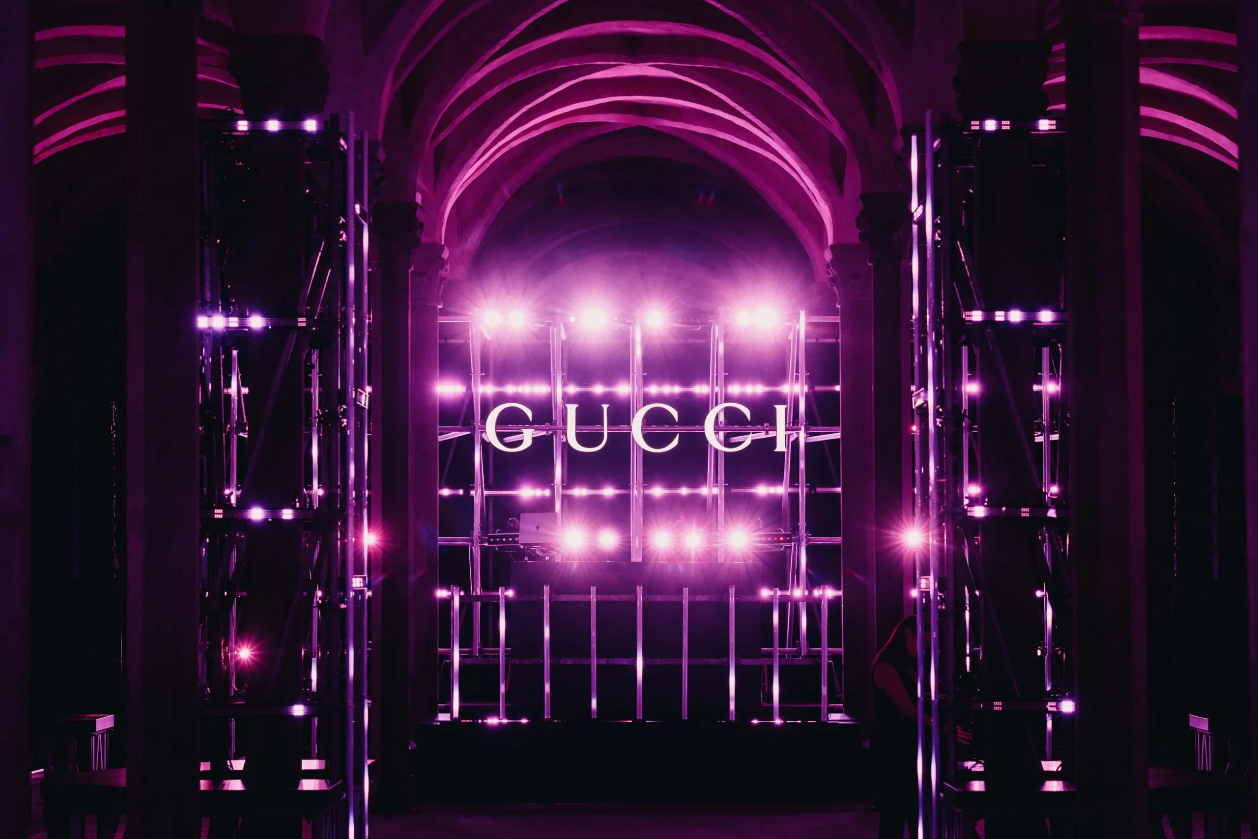Scaffolding stage with a GUCCI sign glowing in pink and purple light under the vaults – Gucci Cruise 2026 Afterparty, Florence, Italy, 2025 – event design