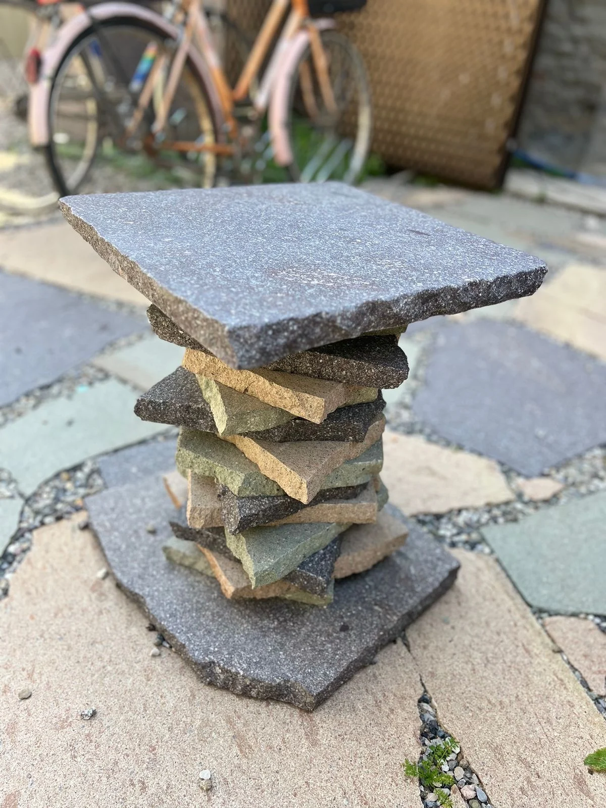 Stool made of stacked porphyry offcuts in grey, green and ochre on a stone-paved courtyard – Frammenti Collection for Porfido Pedretti, Milan, Italy, 2025 – product design