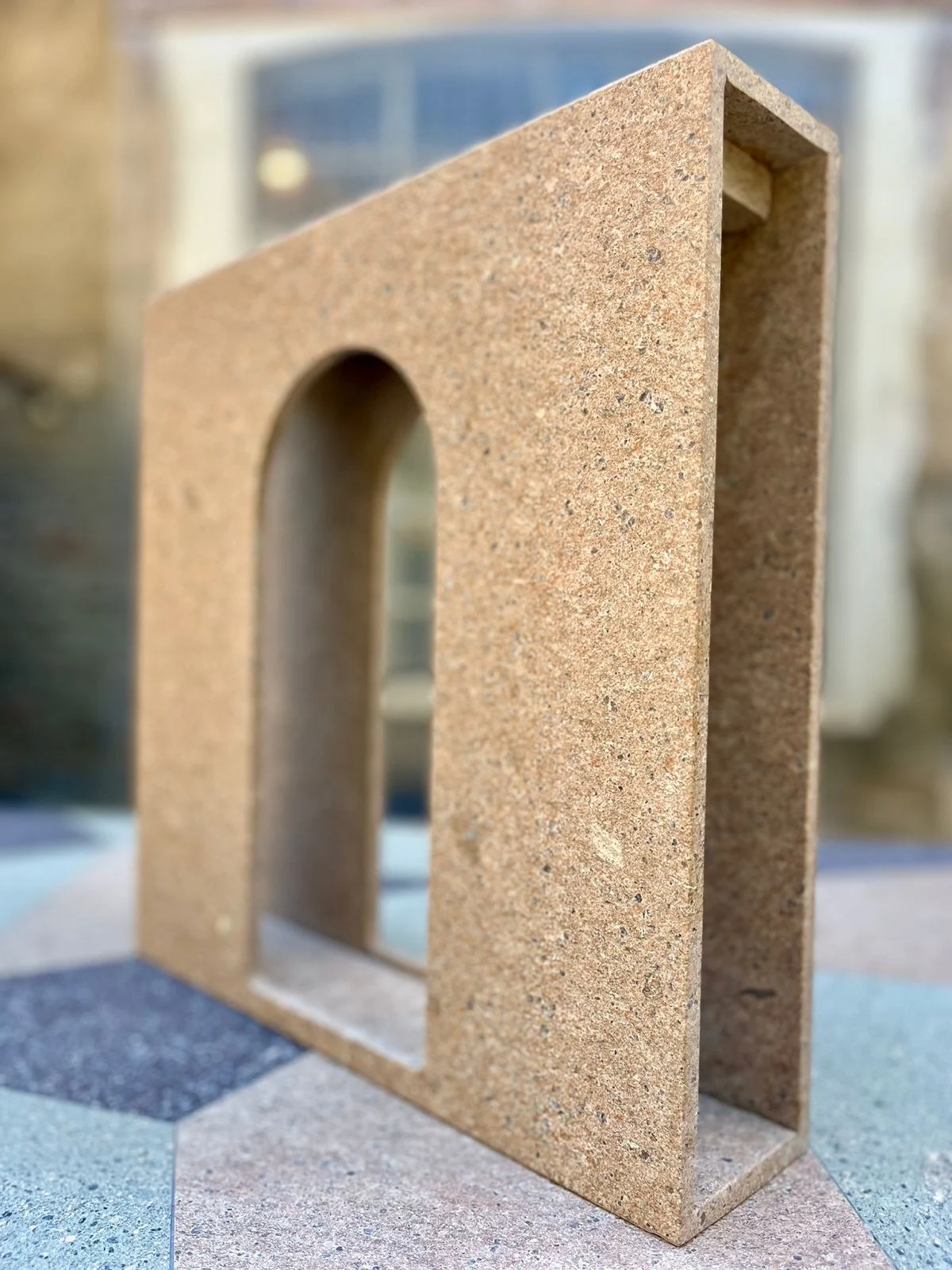 Ochre porphyry shelf piece with an arched opening, on a geometric stone floor – Frammenti Collection for Porfido Pedretti, Milan, Italy, 2025 – product design