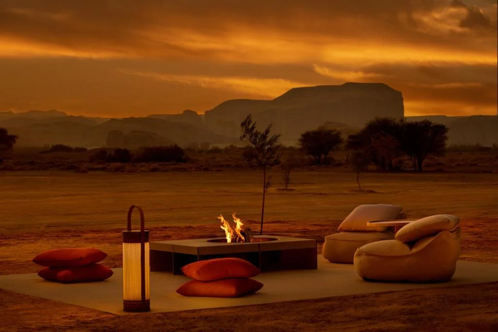 Lantern beside a fire pit and lounge seating in the desert at sunset, rock formations behind – AlUla Lantern for Artemide, Milan, Italy, 2025 – lighting design