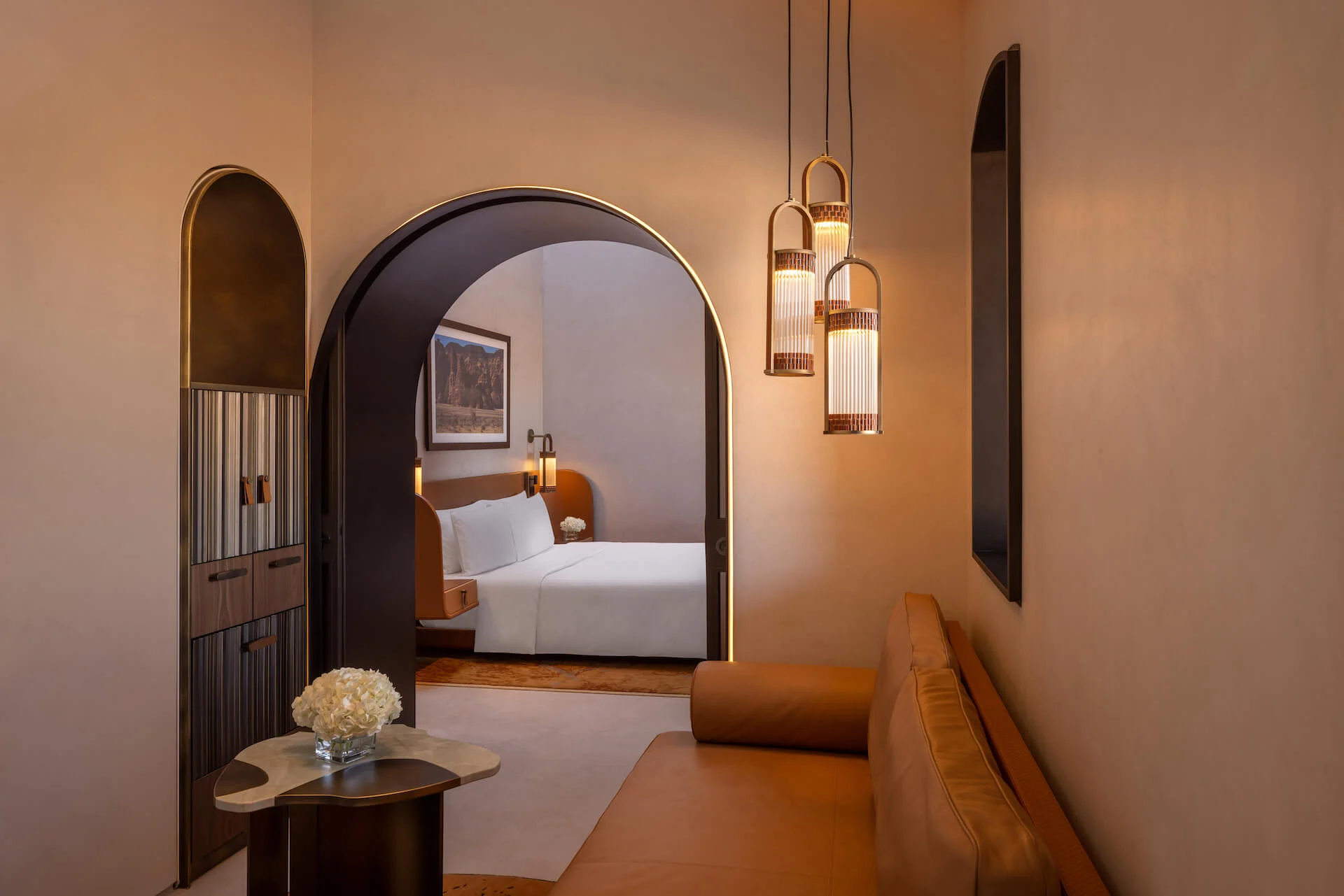 Hotel suite with three lanterns hanging by an arched doorway leading to the bedroom – AlUla Lantern for Artemide, Milan, Italy, 2025 – lighting design