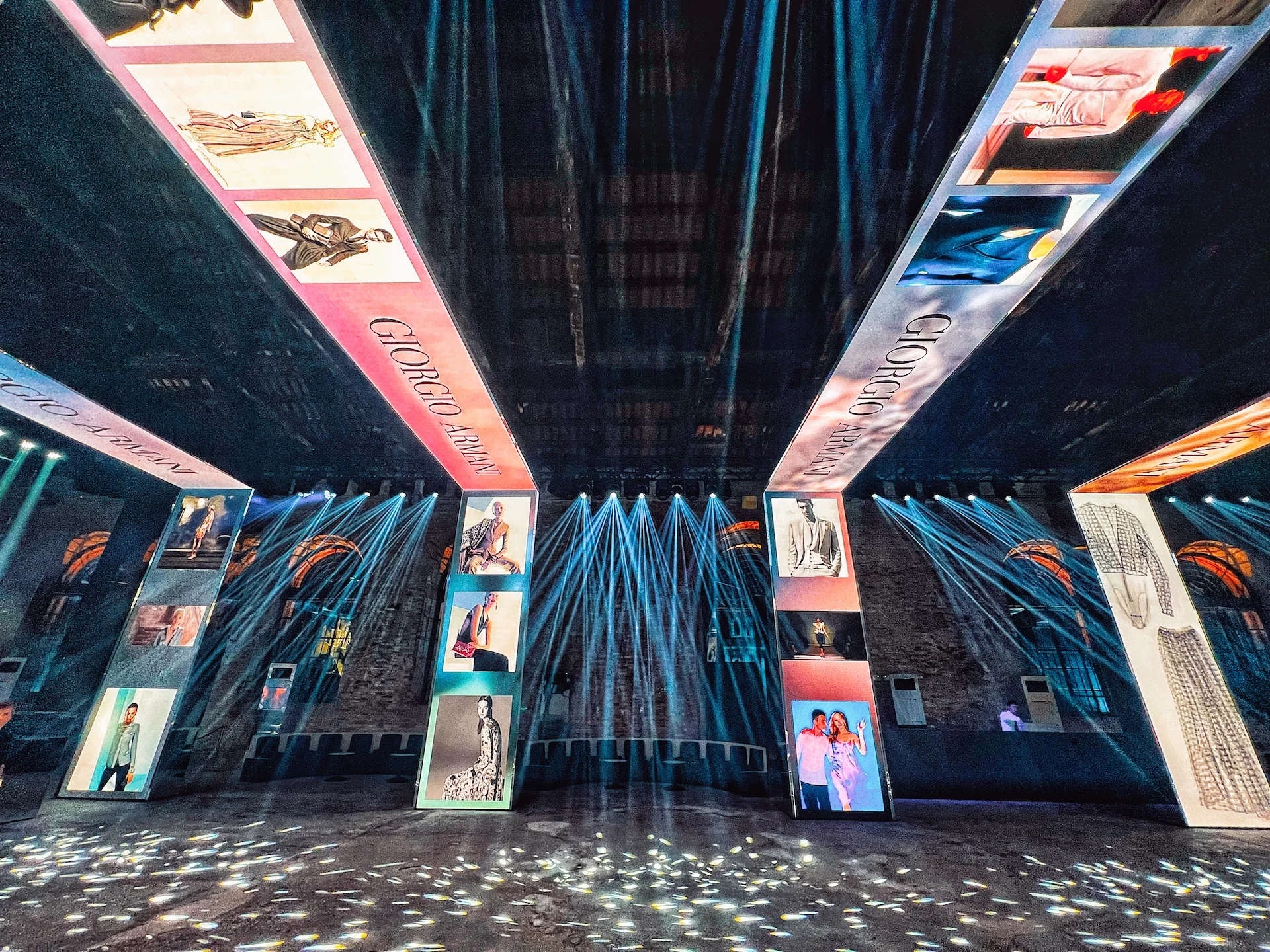 Low view of LED portals showing fashion images, with blue light beams fanning across the brick hall – Armani/Archivio Party at Venice Film Festival, Italy, 2025 – event design
