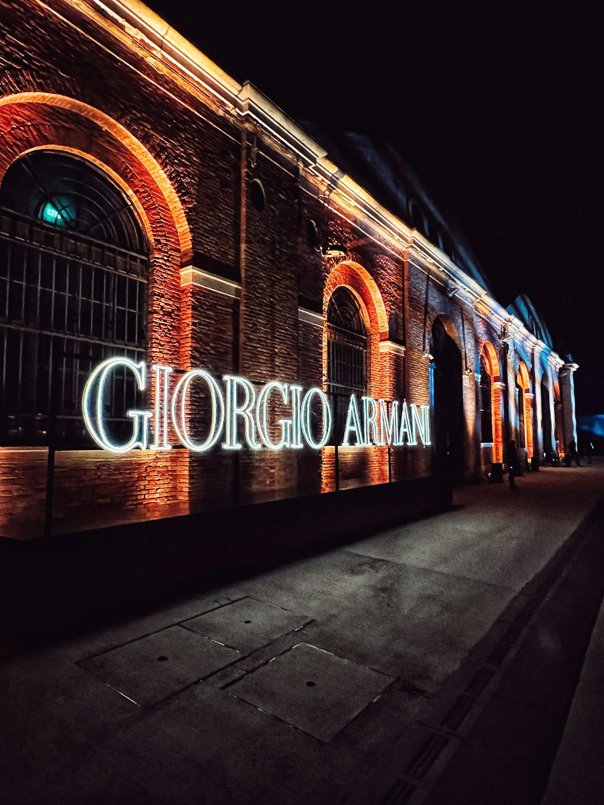 Giorgio Armani in illuminated letters outside the brick arcades of the Arsenale at night – Armani/Archivio Party at Venice Film Festival, Italy, 2025 – event design
