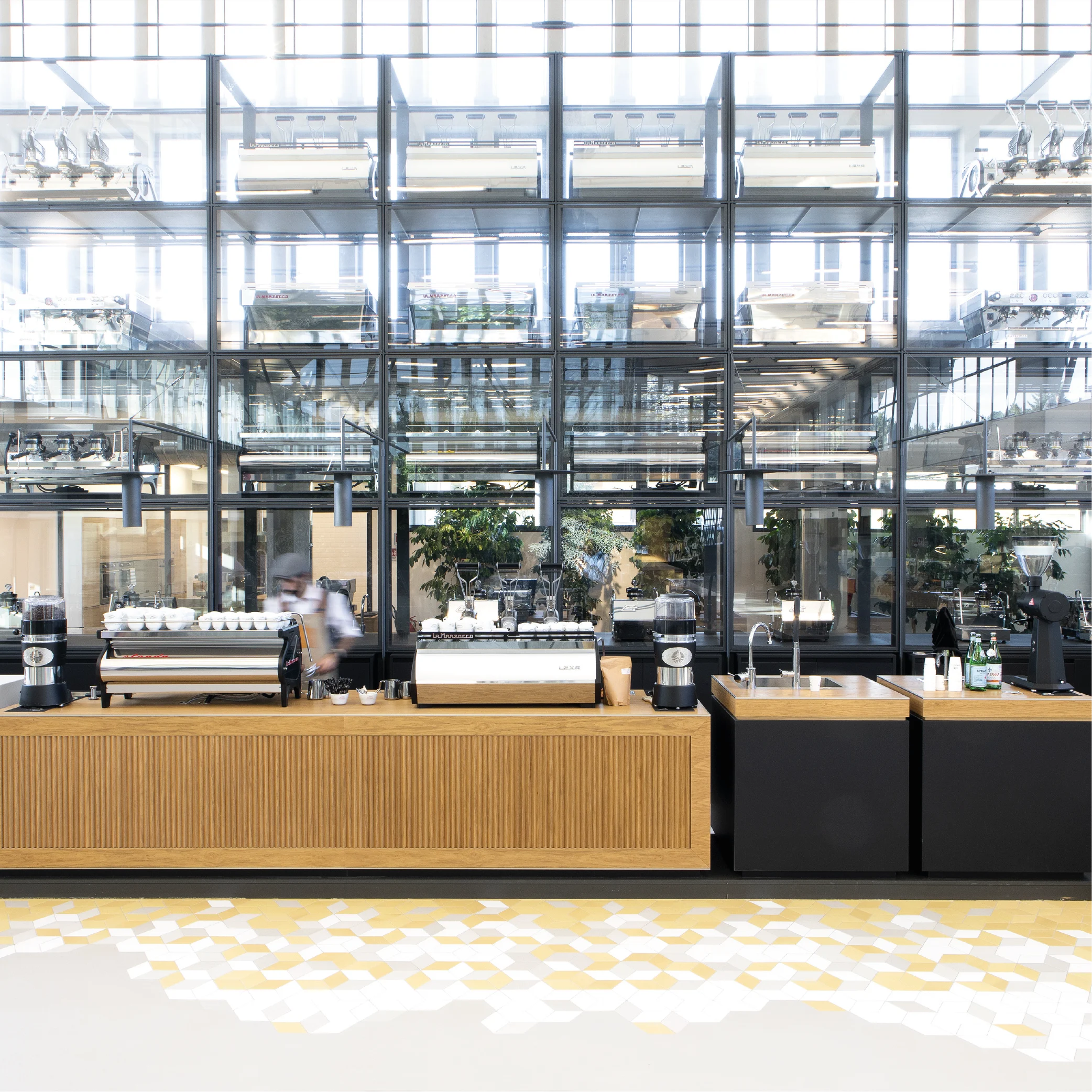 Coffee bar with oak-slatted counter and espresso machines before a tall glass wall of machine displays – La Marzocco Accademia del Caffè Espresso, Florence, Italy, 2018 – interior design
