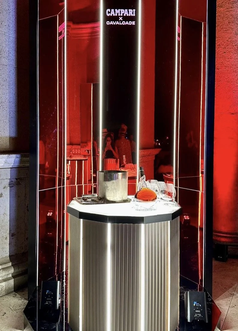 Mirrored octagonal kiosk with an illuminated top holding an ice bucket and glasses – Campari Cavalcade, Rome, Italy, 2023 – event design