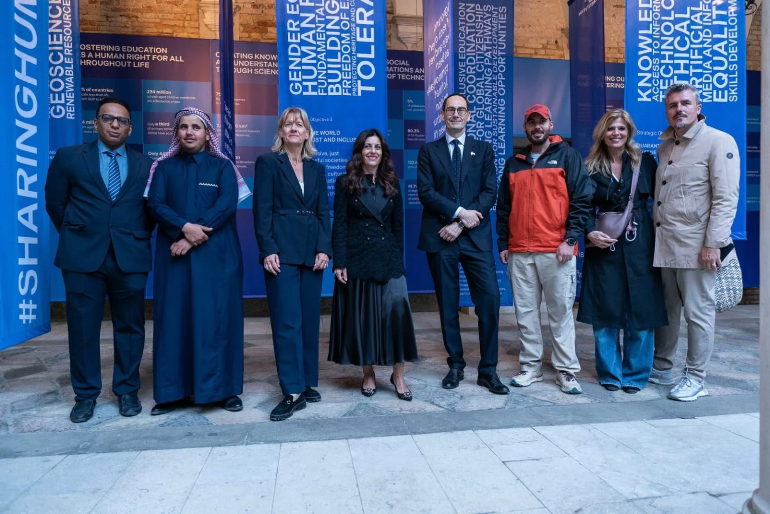 Group of guests posing in front of blue exhibition banners in the Palazzo Zorzi courtyard – Deep Surfaces at Palazzo Zorzi, Venice, Italy, 2025 – exhibition design