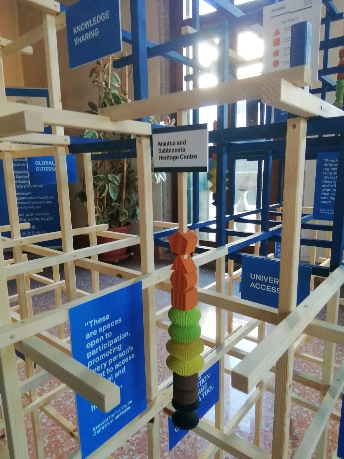 Close-up inside the wooden lattice: a stack of colourful 3D-printed pieces among blue captions and project labels – Deep Surfaces at Palazzo Zorzi, Venice, Italy, 2025 – exhibition design