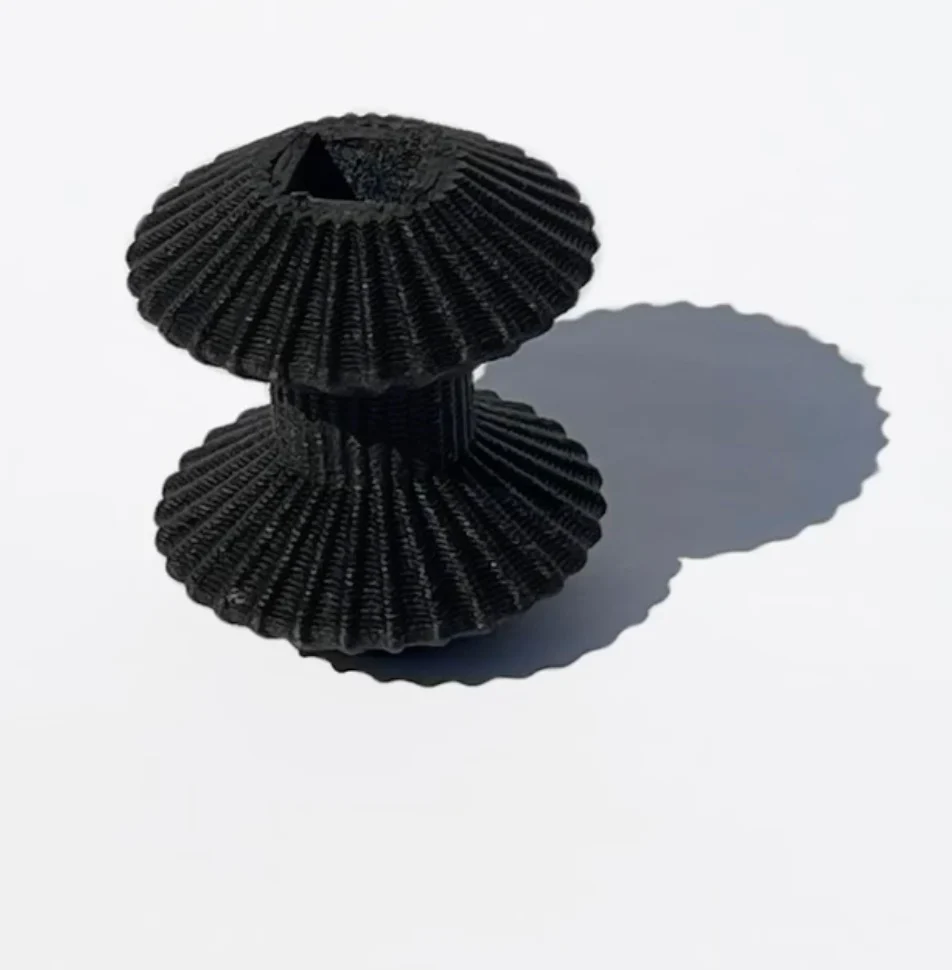 Black 3D-printed ribbed spool-shaped piece on a white background – Deep Surfaces at Palazzo Zorzi, Venice, Italy, 2025 – exhibition design