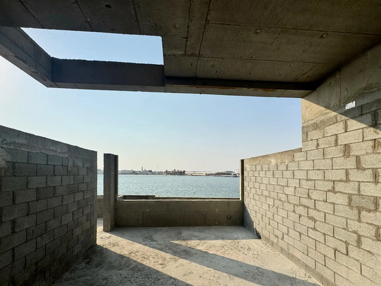 Unfinished concrete-block room framing a view of the sea under an open roof slab – Radic Residences, Jeddah, Saudi Arabia, 2025 – architecture, under construction