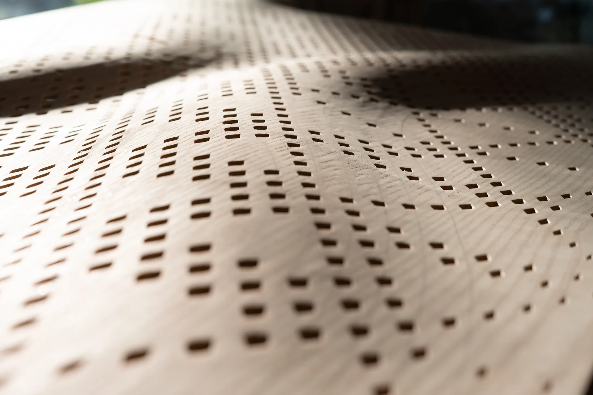 Close-up of a perforated curved wooden panel with rows of small rectangular holes – Najdi Acoustic Panels for Strong by Form, 2025 – product design