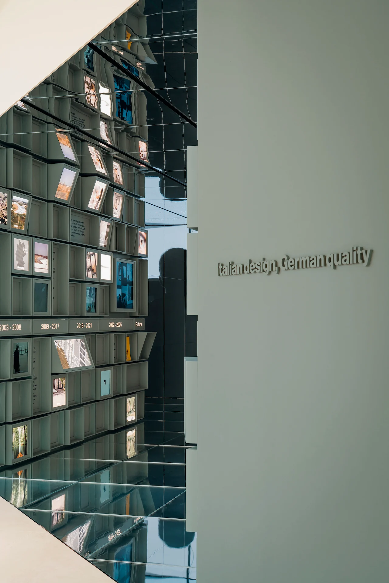 Mirrored entrance with the modular timeline wall and the wall lettering Italian design, German quality – Porcelaingres Brand Narrative Space, Castellarano, Italy, 2025 – showroom design