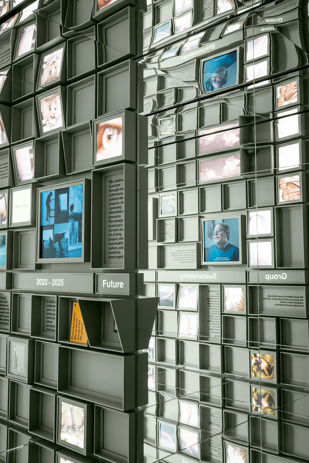 Cube wall with portraits and video screens reflected in the mirrored ceiling and side walls – Porcelaingres Brand Narrative Space, Castellarano, Italy, 2025 – showroom design