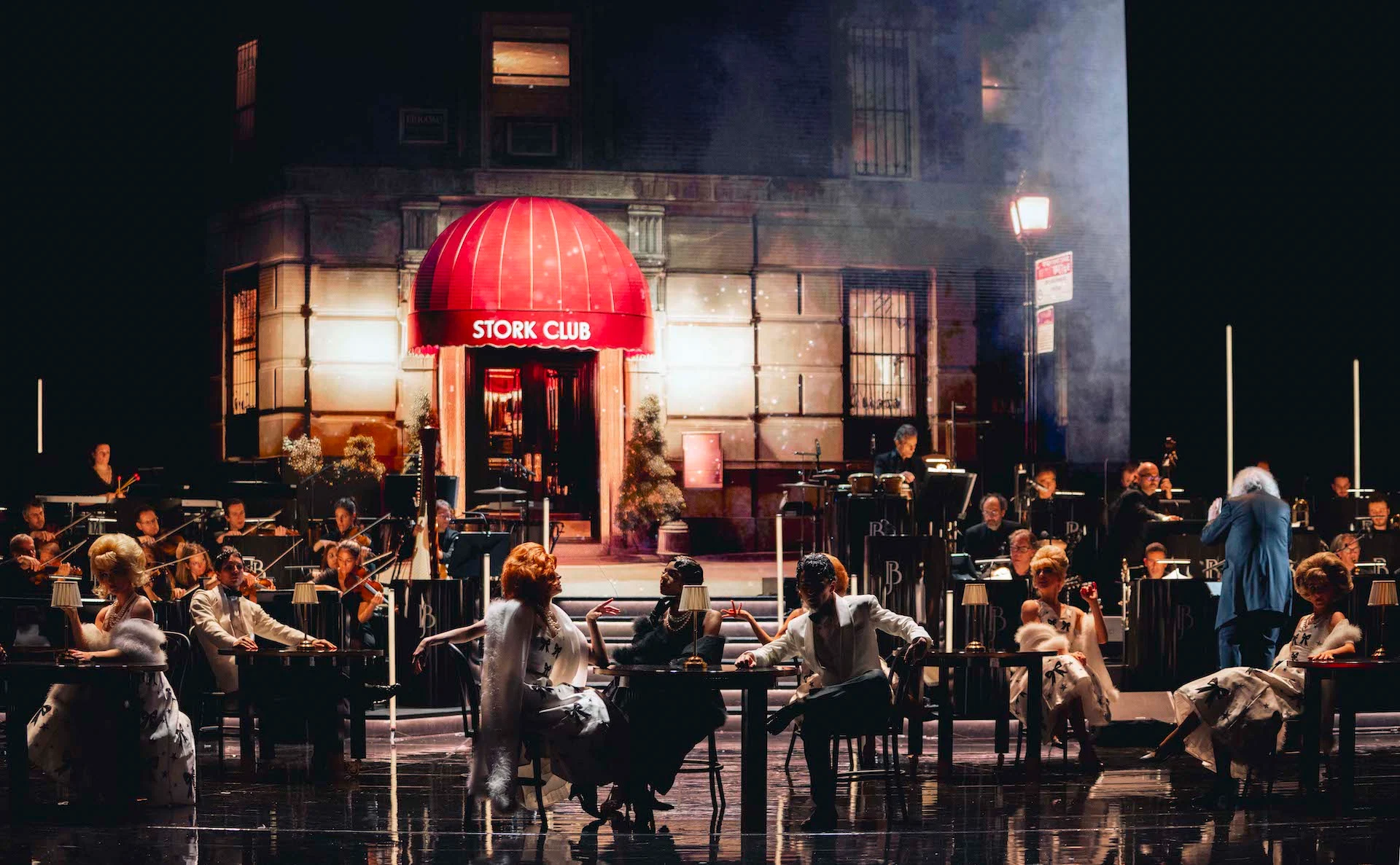 Night street set with a red Stork Club awning, performers seated at tables and the orchestra in the haze – Bonsoir Monte-Carlo, Monte Carlo, Monaco, 2025 – stage design