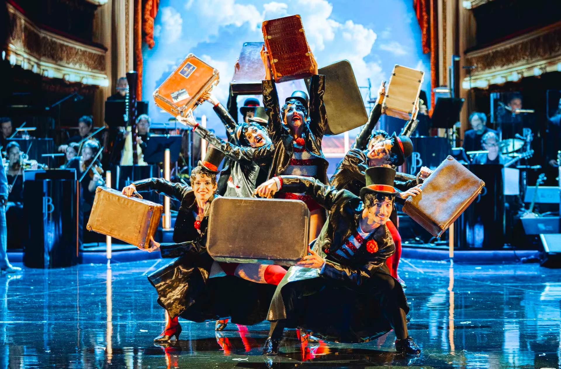 Dancers in top hats raising vintage suitcases against a painted sky backdrop – Bonsoir Monte-Carlo, Monte Carlo, Monaco, 2025 – stage design