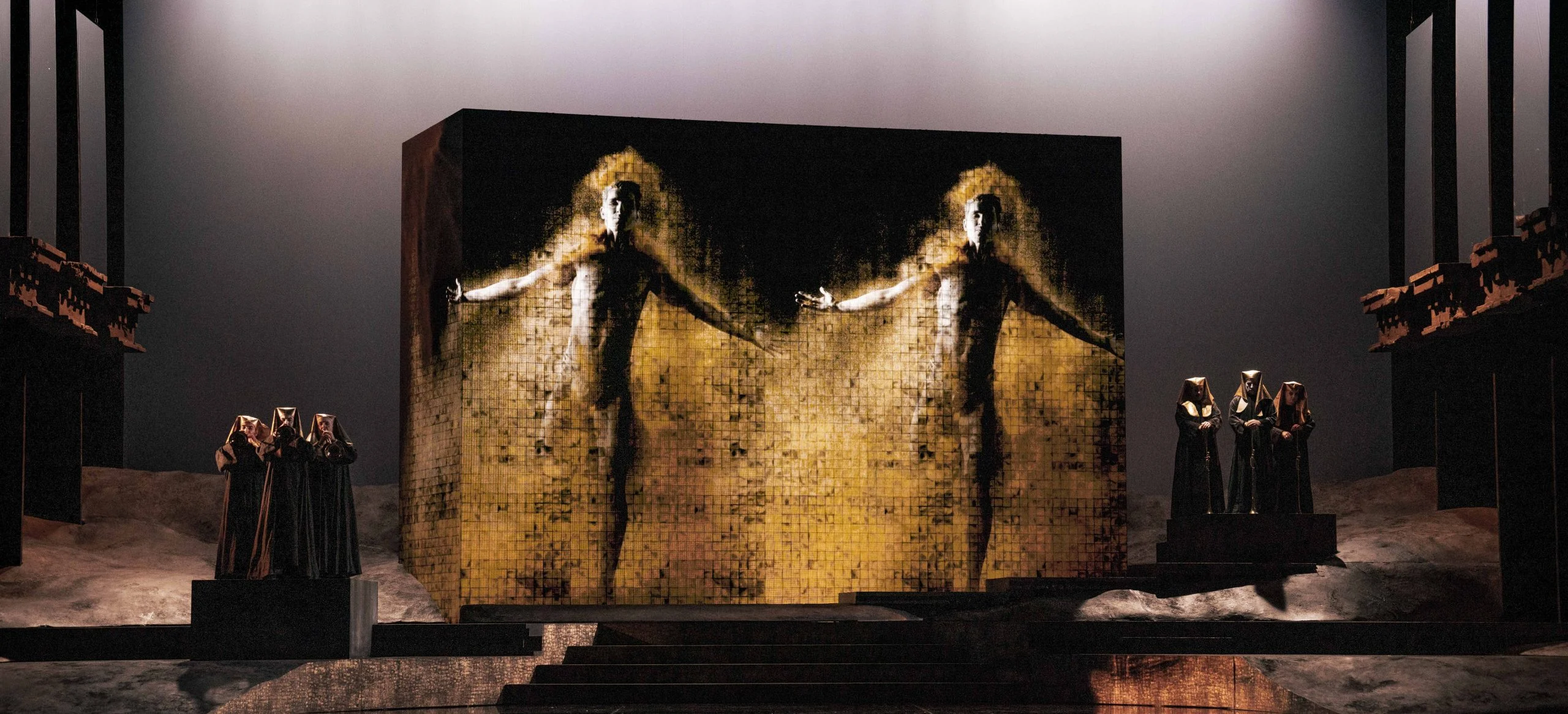 Monumental block with projections of two golden human figures, hooded figures standing on either side – Aida at Opéra de Monte-Carlo, Monte Carlo, Monaco, 2025 – set design