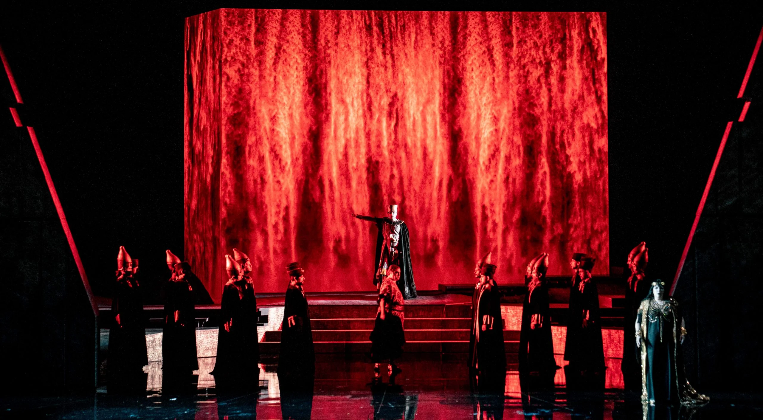 Block projected with flame-red textures, priests in tall headdresses lined up in front – Aida at Opéra de Monte-Carlo, Monte Carlo, Monaco, 2025 – set design