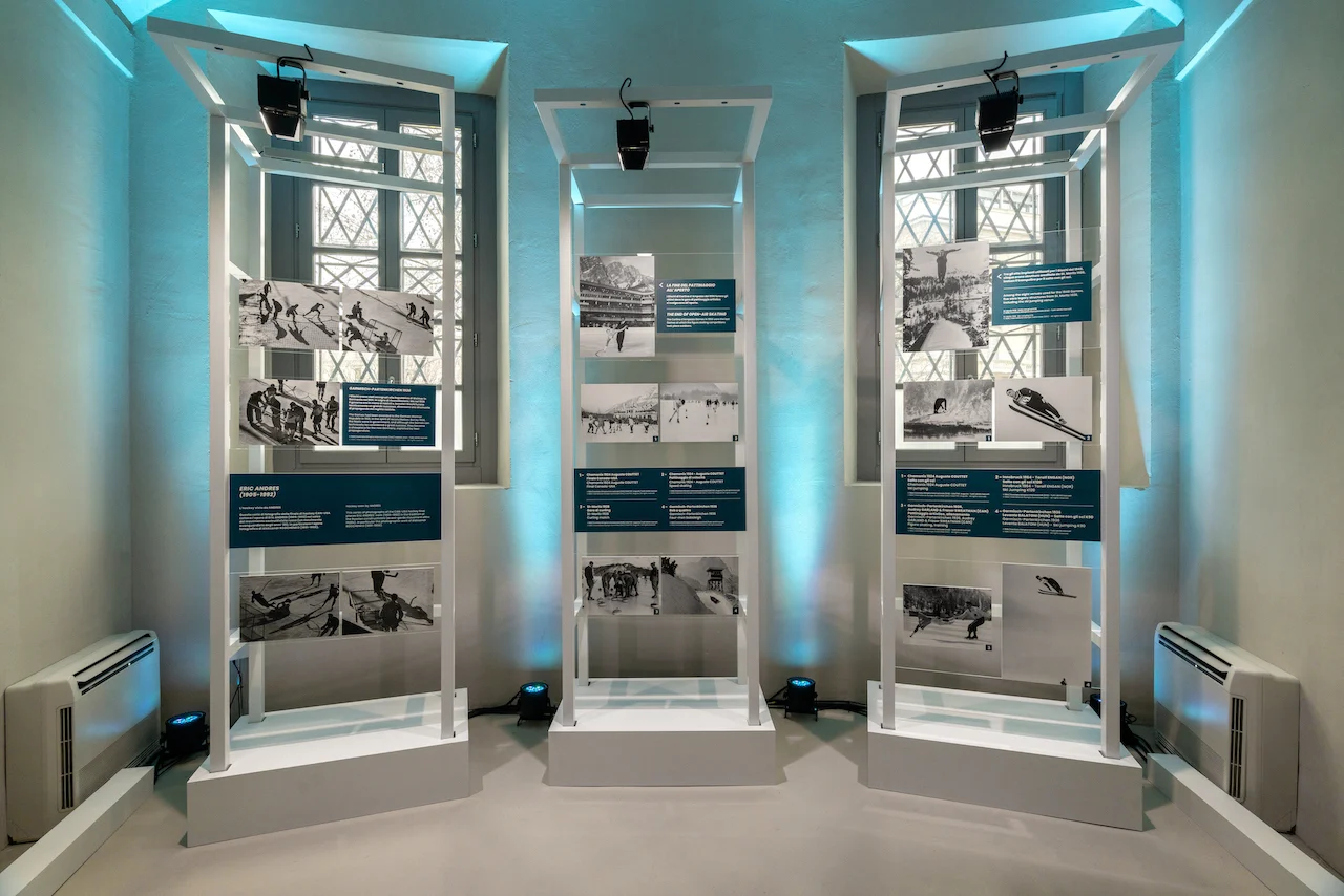 Three white frames with black-and-white photos of historic winter sports, set before tall windows – Clubhouse 26 Milano, Italy, 2026 – hospitality design