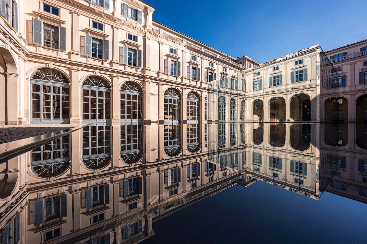 Arched courtyard façades of Palazzo Serbelloni mirrored in the black reflecting pool under a blue sky – Samsung House at Palazzo Serbelloni, Milan, Italy, 2026 – interior design