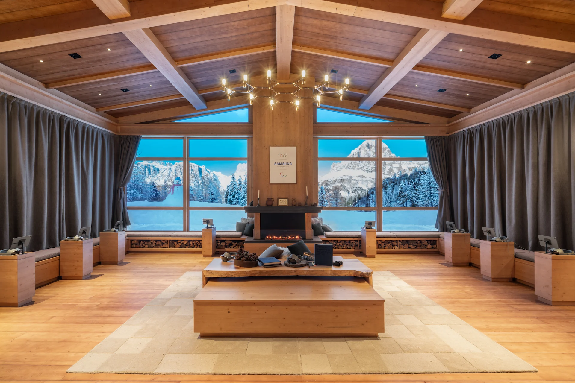 Alpine-style lounge with timber ceiling, fireplace and large windows framing snowy mountain views – Samsung House at Palazzo Serbelloni, Milan, Italy, 2026 – interior design