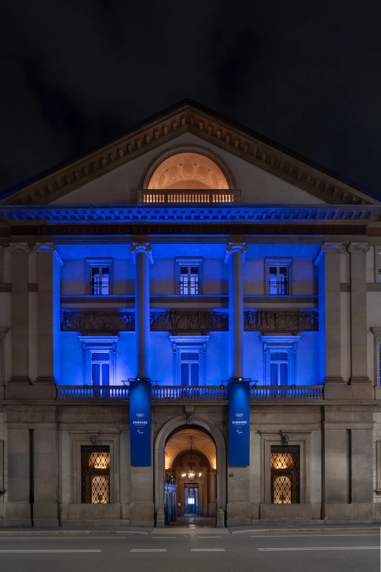 Palazzo Serbelloni façade at night washed in blue light, Samsung banners at the entrance – Samsung House at Palazzo Serbelloni, Milan, Italy, 2026 – interior design