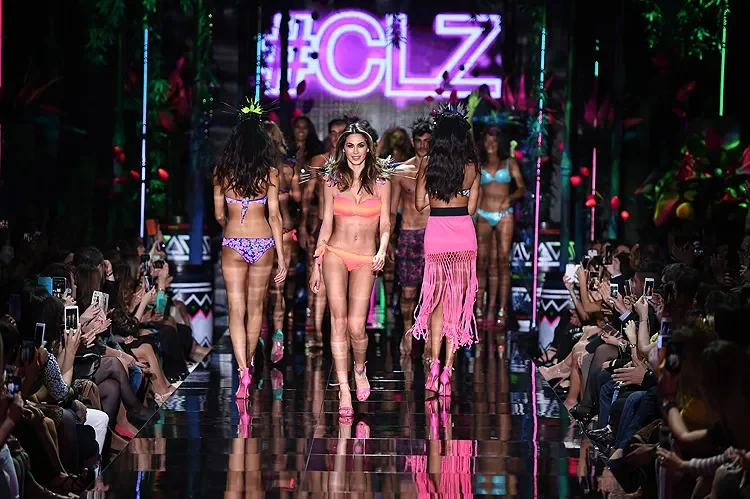 Models in swimwear walking the mirrored runway toward the audience beneath the pink #CLZ neon sign – Calzedonia SS15 Collection, Italy, 2015 – fashion show set design