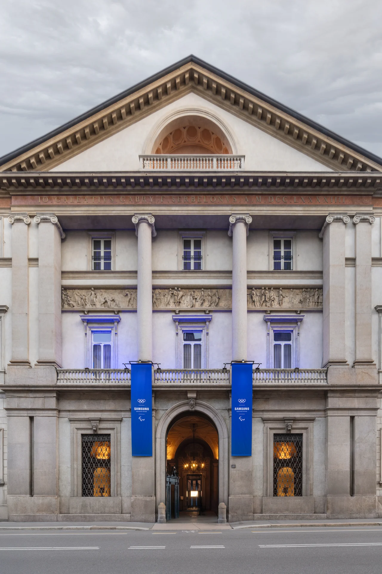 Neoclassical façade of Palazzo Serbelloni by day, two blue Samsung banners beside the entrance – Samsung House at Palazzo Serbelloni, Milan, Italy, 2026 – interior design