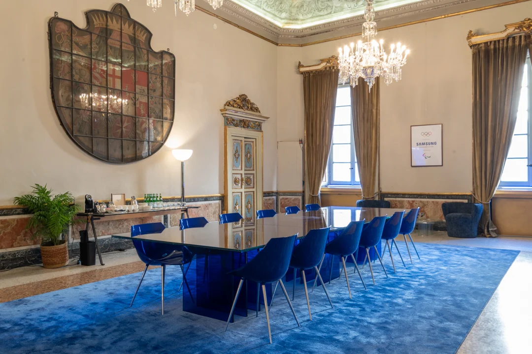STRACTA glass table with blue chairs set as a meeting table in a frescoed hall with chandeliers – STRACTA Table for Driade, Milan, Italy, 2026 – product design
