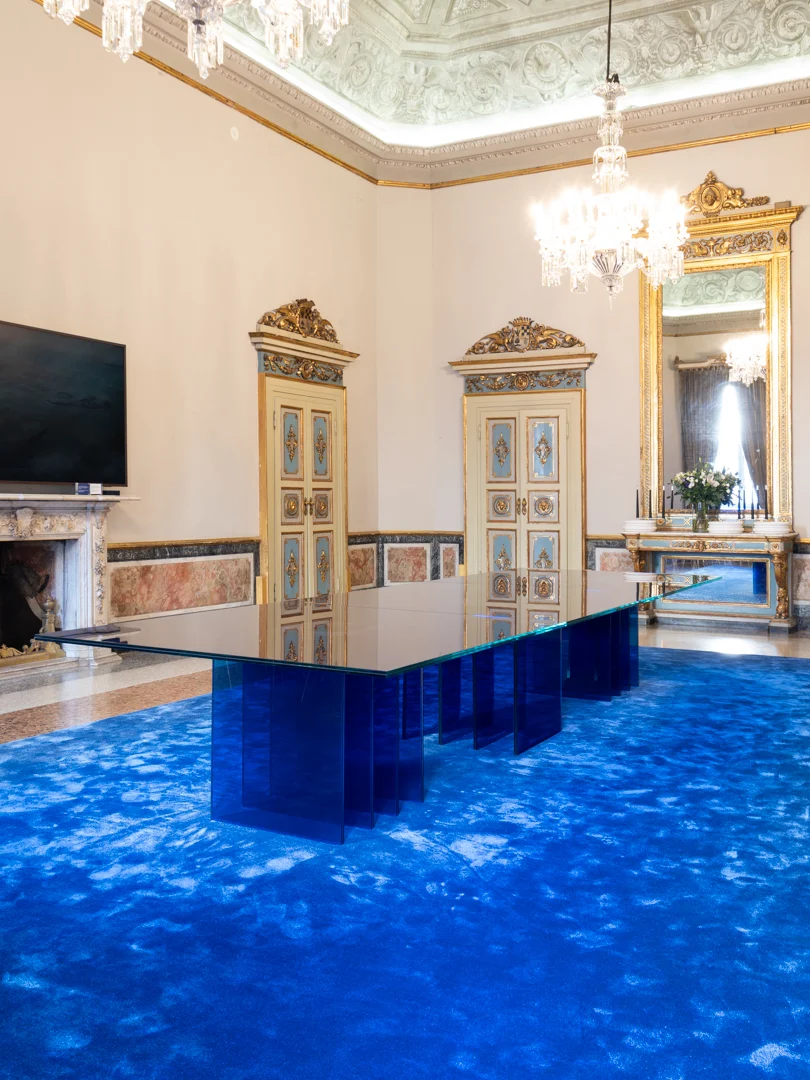 STRACTA table with layered blue glass legs on a blue rug, in a palazzo room with gilded doors – STRACTA Table for Driade, Milan, Italy, 2026 – product design
