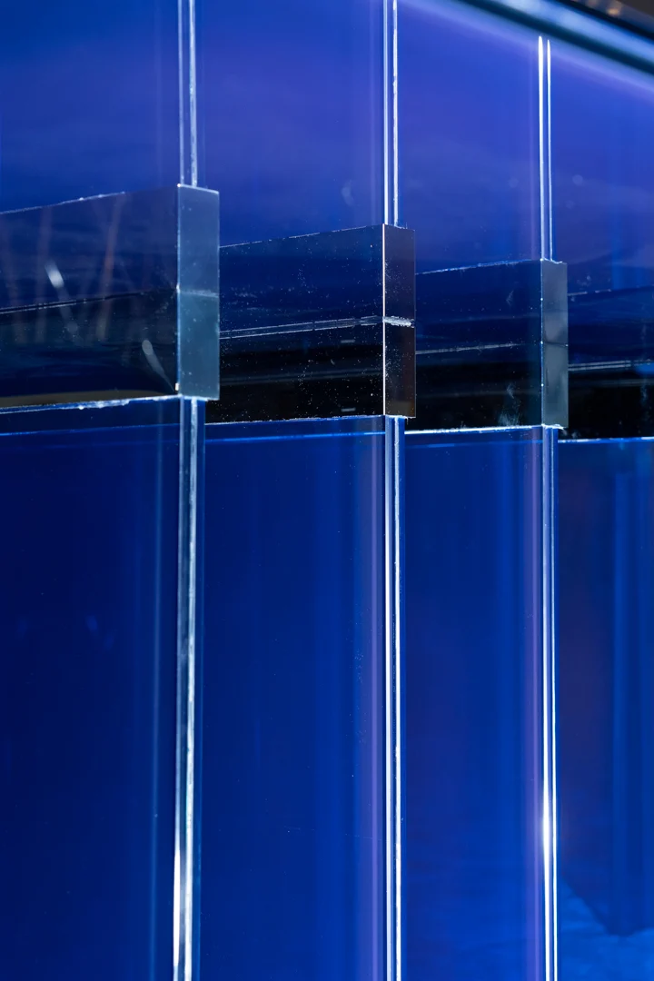 Close-up of glass joining blocks between the layered blue glass panels of the table base – STRACTA Table for Driade, Milan, Italy, 2026 – product design