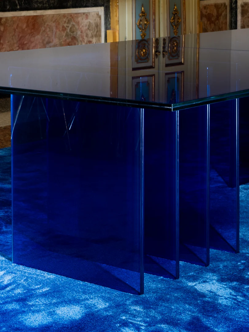 Corner of the STRACTA table: clear glass top resting on staggered blue glass panels – STRACTA Table for Driade, Milan, Italy, 2026 – product design