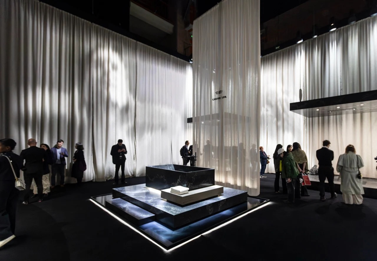 GROHE SPA Aqua Sanctuary: dark stone bath on a lit platform, surrounded by tall white curtains and visitors – GROHE SPA Aqua Sanctuary at Fuorisalone, Milan, Italy, 2026 – installation design