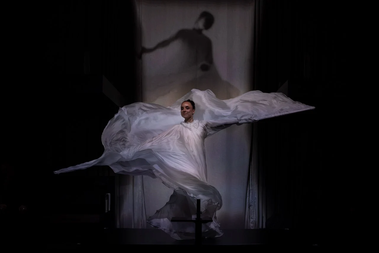 Dancer swirling flowing white fabric on a dark stage, her shadow projected on the curtain behind – GROHE SPA Aqua Sanctuary at Fuorisalone, Milan, Italy, 2026 – installation design
