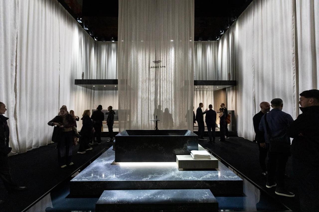 Long view of the curtained hall with a black stone bath on a lit plinth, visitors along the sides – GROHE SPA Aqua Sanctuary at Fuorisalone, Milan, Italy, 2026 – installation design