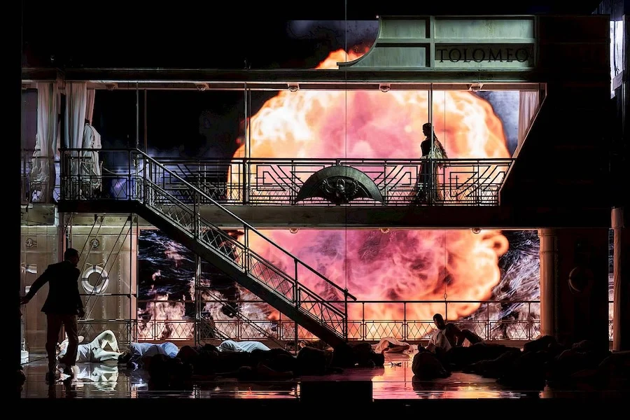 Darkened set with a huge orange explosion on the screen and bodies lying on the floor – Giulio Cesare in Egitto at Opéra de Monte-Carlo, Monte Carlo, Monaco, 2025 – set design