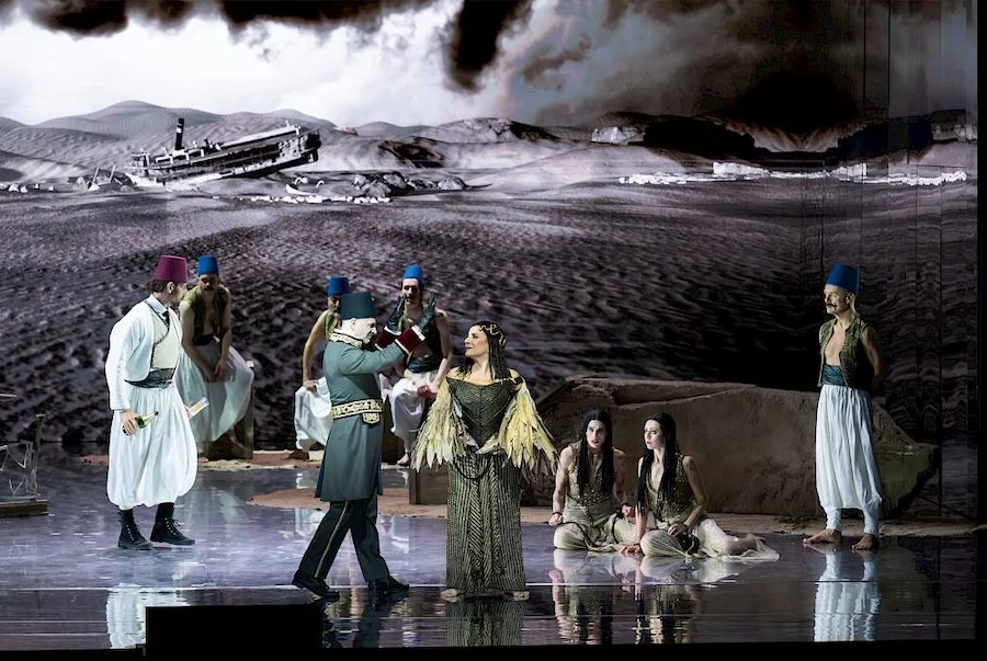 Singers in costume and fezzes before a projected desert with a stranded steamboat – Giulio Cesare in Egitto at Opéra de Monte-Carlo, Monte Carlo, Monaco, 2025 – set design