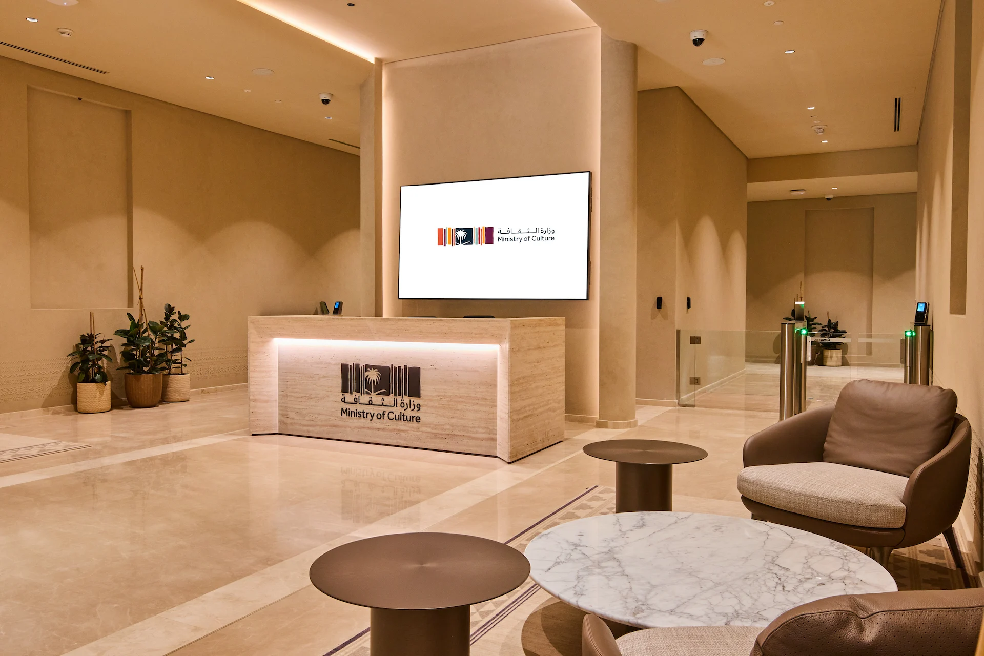 Ministry of Culture reception: travertine desk with logo, wall screen and armchairs around marble tables – MOC Headquarters, Diriyah, Saudi Arabia, 2026 – interior design