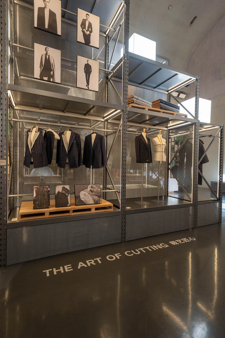 The Art of Cutting section: dark tailored jackets and black-and-white portraits on metal shelving – Max Mara The Max! at Long Museum, Shanghai, China, 2026 – exhibition design