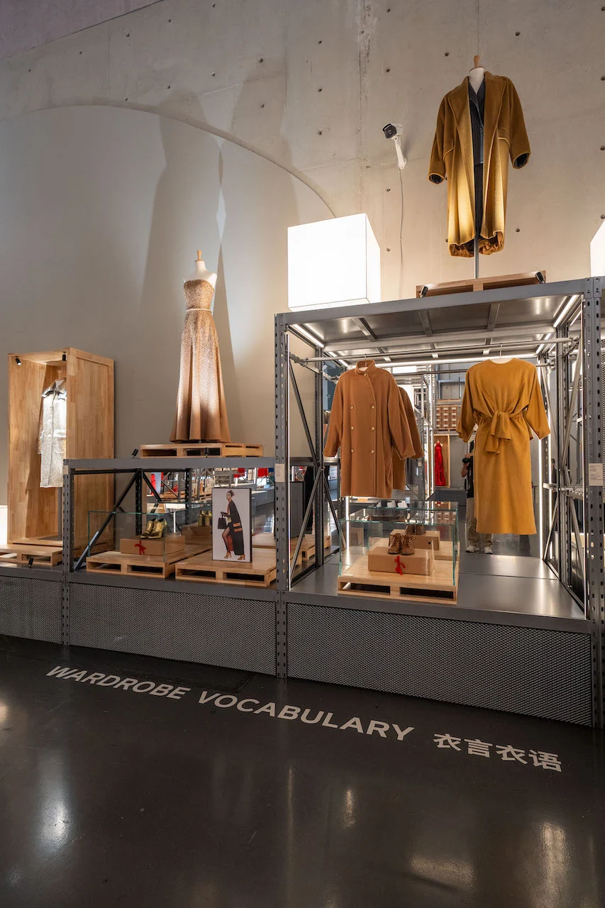 Wardrobe Vocabulary section: camel and mustard garments and an evening gown displayed on metal shelving – Max Mara The Max! at Long Museum, Shanghai, China, 2026 – exhibition design