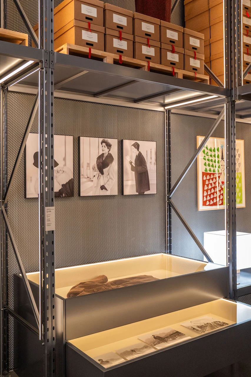 Metal shelving with archive boxes, black-and-white fashion photographs and illuminated display cases below – Max Mara The Max! at Long Museum, Shanghai, China, 2026 – exhibition design
